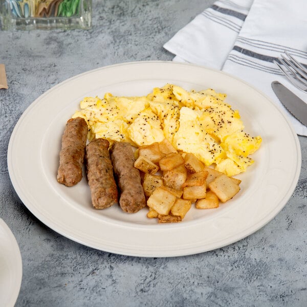 A Homer Laughlin ivory china plate with sausage, eggs, and potatoes on it.