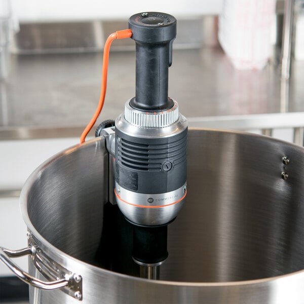 A KitchenAid immersion blender with a cord in a pot.