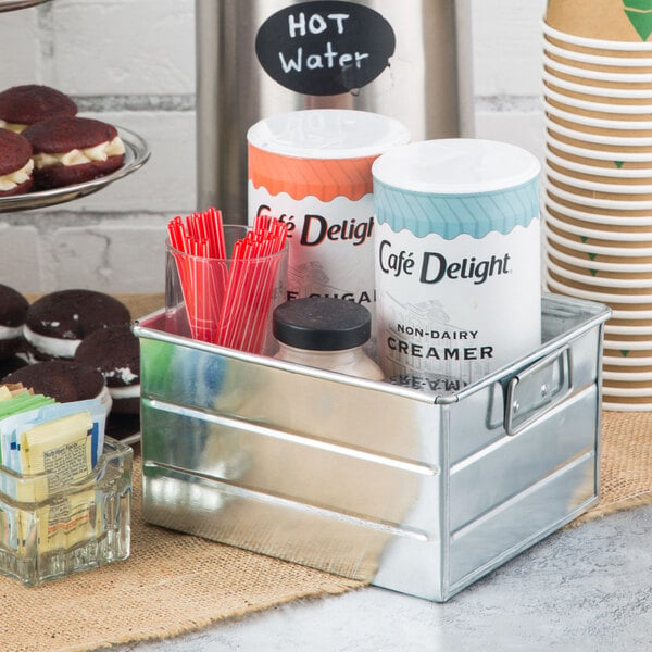 A galvanized steel American Metalcraft condiment caddy on a table with condiments, cookies, sandwiches, and straws.