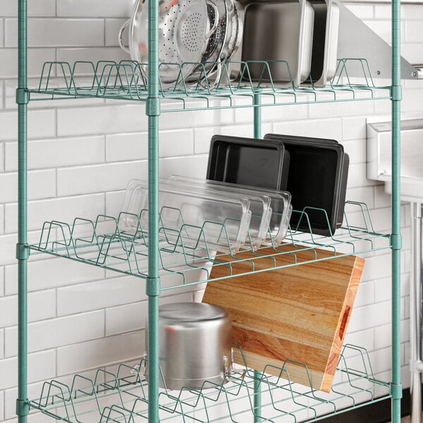 A Regency green epoxy wire drying rack shelf with utensils and pans on it.