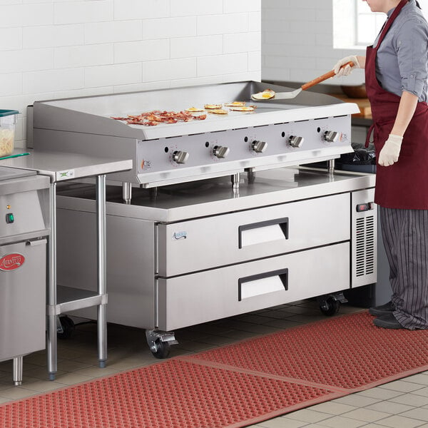 A woman using a Cooking Performance Group gas countertop griddle to cook food.