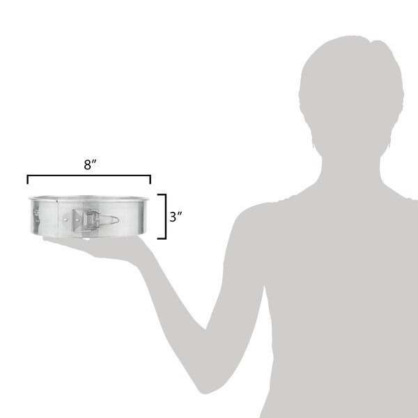 A woman holding a Chicago Metallic aluminum springform cake pan with measurements.