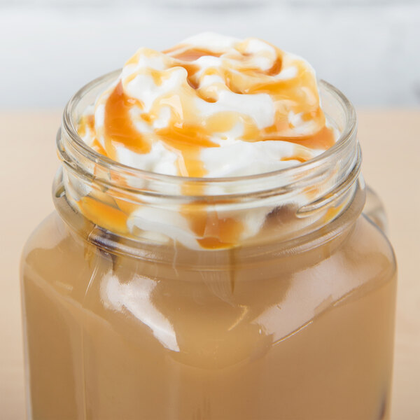 A glass jar of Ghirardelli Sea Salt Caramel Flavoring Sauce with a liquid in it.