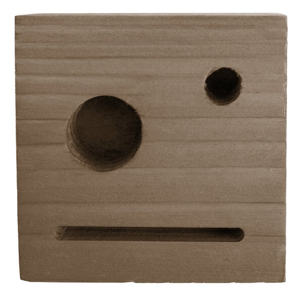 A weathered walnut wood block with two circular holes in it.