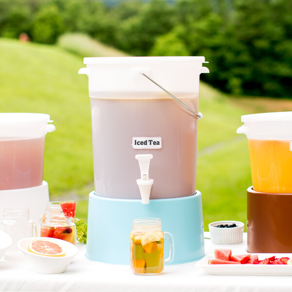 A white Choice beverage dispenser with a blue base filled with a pink drink and lemons.