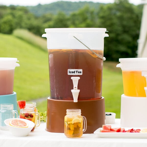 A Choice translucent beverage dispenser with brown base filled with yellow and pink drinks on a table.