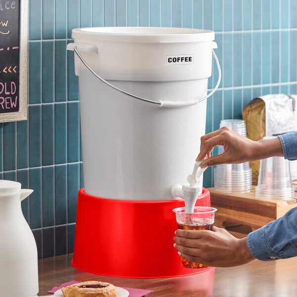 A large white beverage dispenser with a red base and a spigot, labeled for coffee.