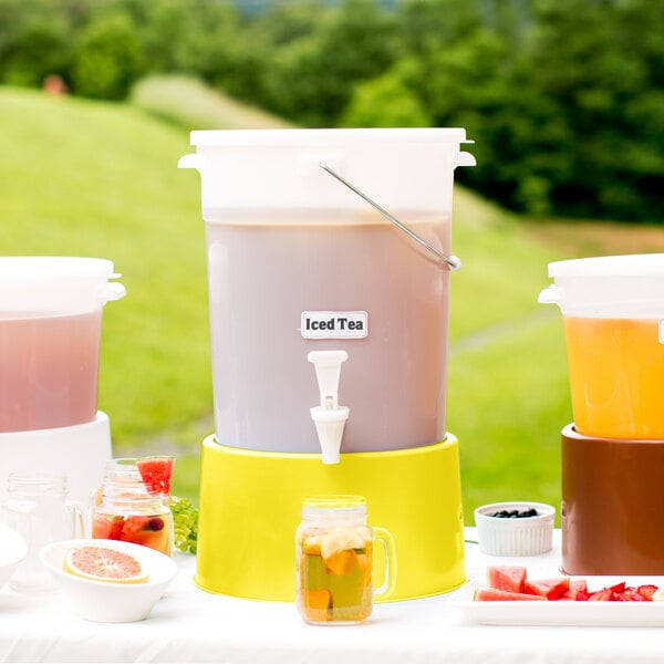 A table with a Choice white beverage dispenser with a yellow base filled with yellow liquid and lemon slices.