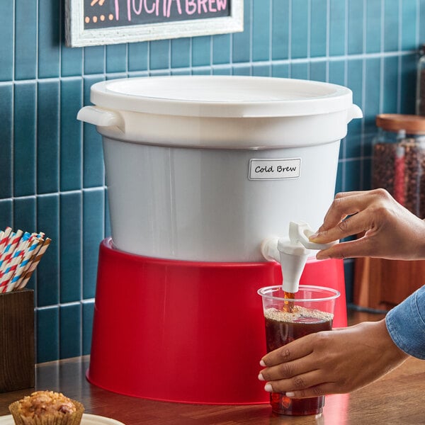 A white 3-gallon beverage dispenser with a red base and a spigot for serving drinks.