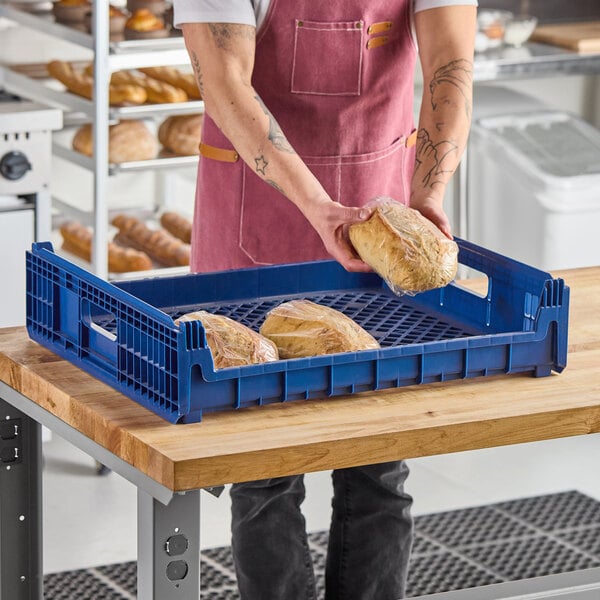 A blue plastic bakery bread tray holding loaves of bread, placed on a wooden table.
