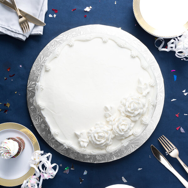 A white cake on a silver round cake board.