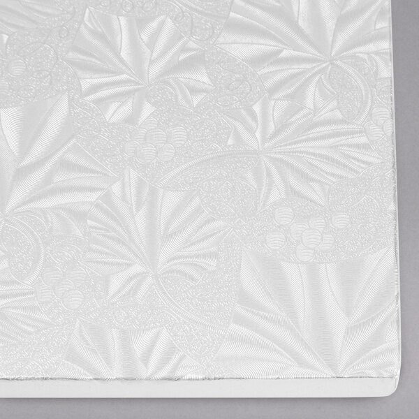 A white surface with a pattern on a white Enjay cake board.