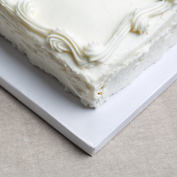 A white Enjay cake board with a white cake and frosting on top.
