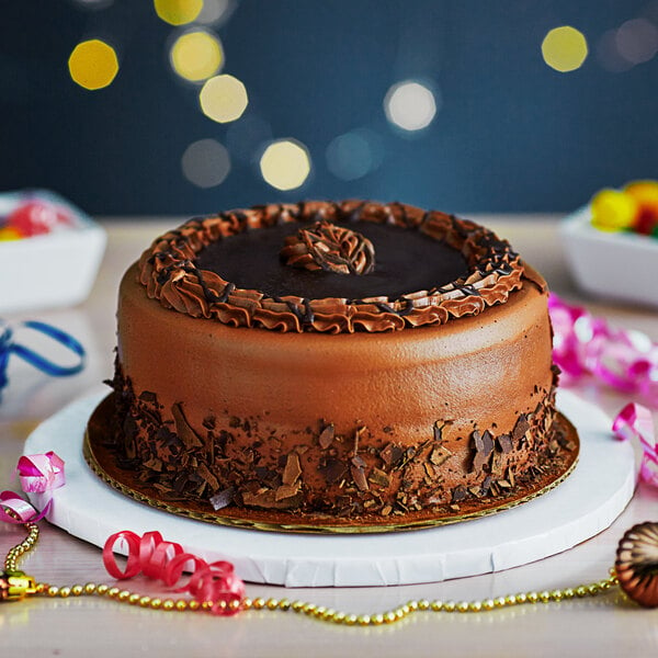 A chocolate cake on a white Enjay round cake drum on a table.