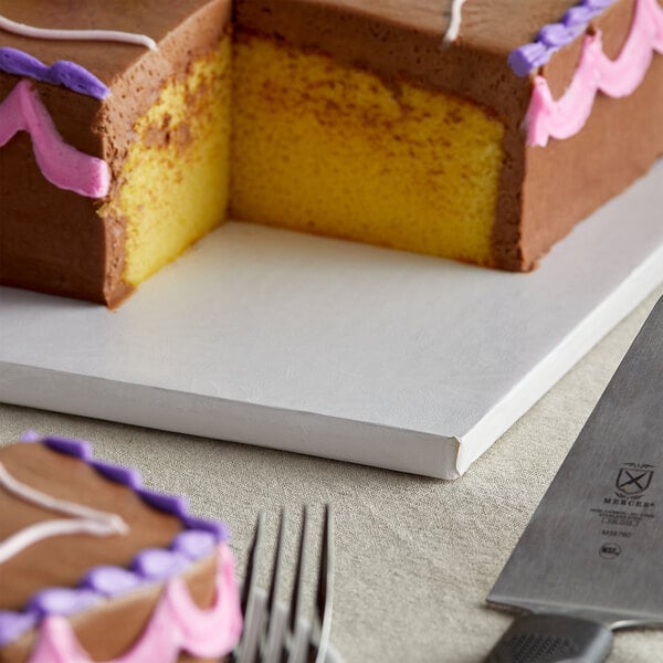 A white cake on an Enjay Fold-Under Cake Board with a slice cut out.