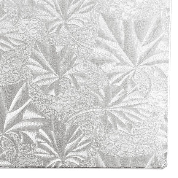 A close-up of a white Enjay silver cake board with floral designs.