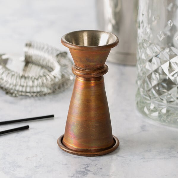 An American Metalcraft antique copper Japanese style jigger on a table.