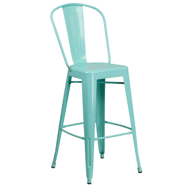 A green metal bar stool with a backrest and drain hole seat.