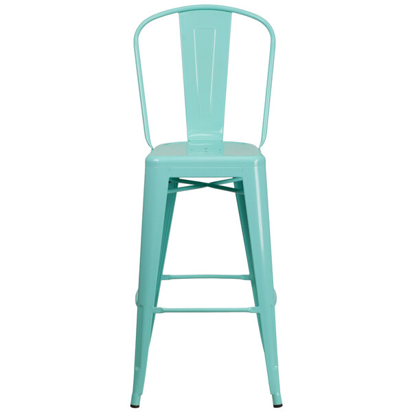 A green metal bar stool with a backrest and a white seat with a hole in it.