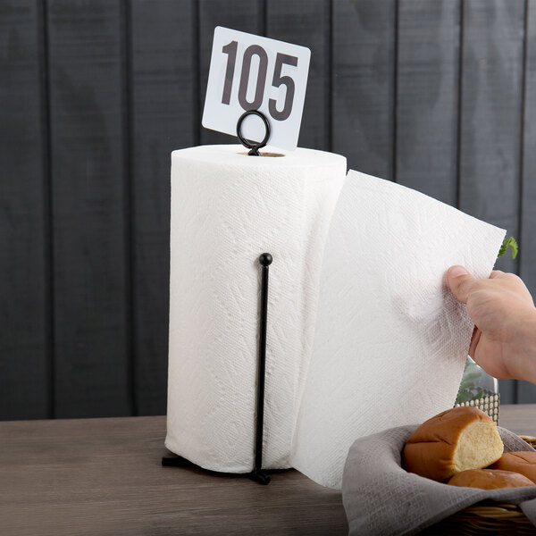 A hand holding a paper towel with a black curved wire holder with a card holder.