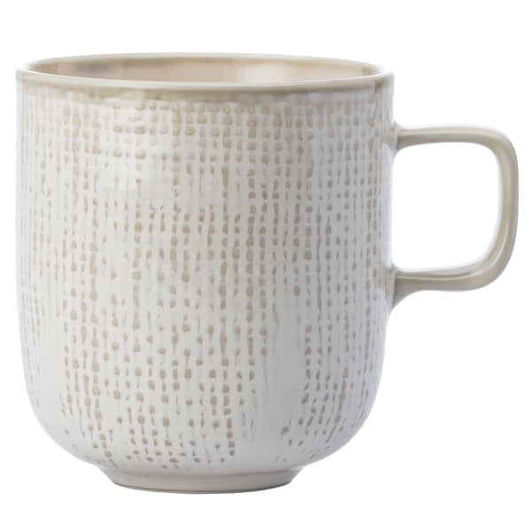 A white Oneida Knit porcelain mug with a speckled tan design and handle.