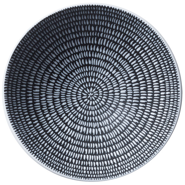 A white porcelain pedestal bowl with a black and white circular pattern.