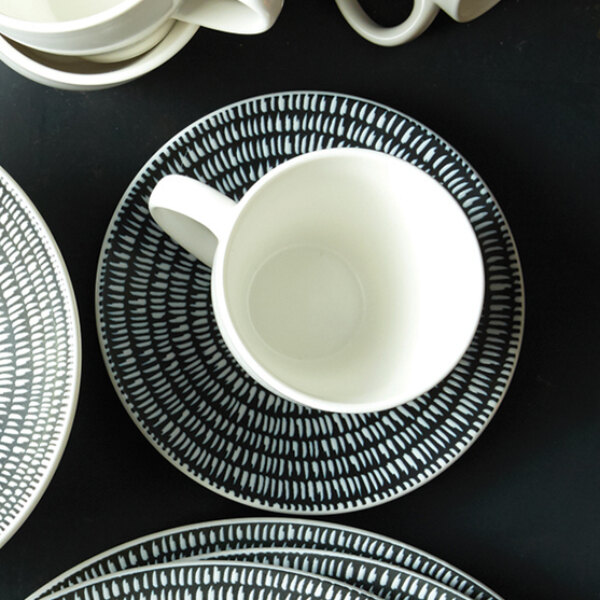 A white saucer with a black and white pattern.