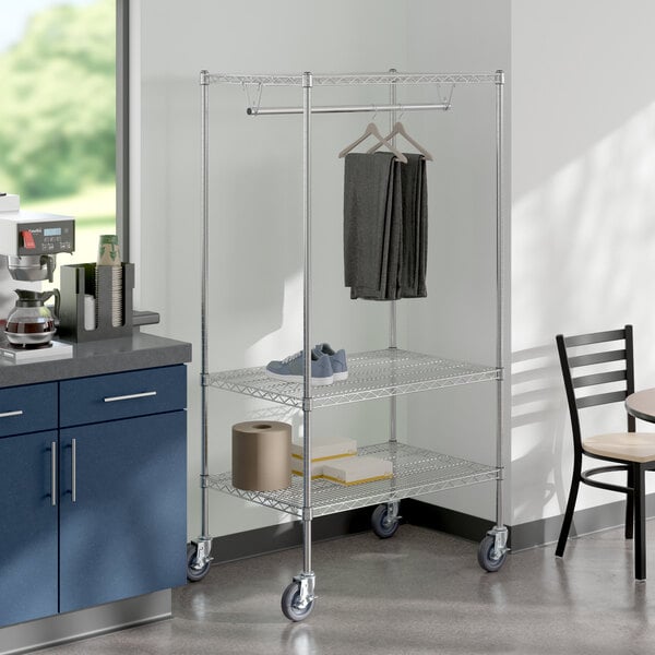 A chrome Regency mobile garment rack with clothes on it.