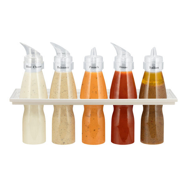 Five squeeze bottles filled with different salad dressings are arranged in a white holder, each labeled with the dressing type.