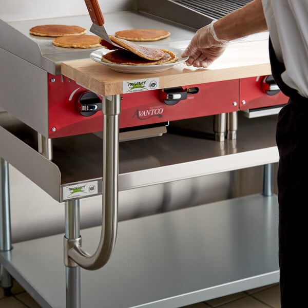 A chef uses a Regency wooden cutting board to slice pancakes on a counter.