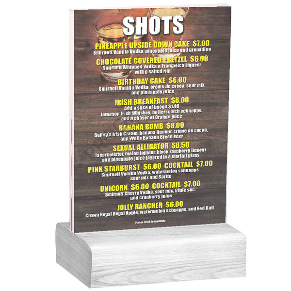 A clear acrylic table tent with a white wood base holding a menu on a table.