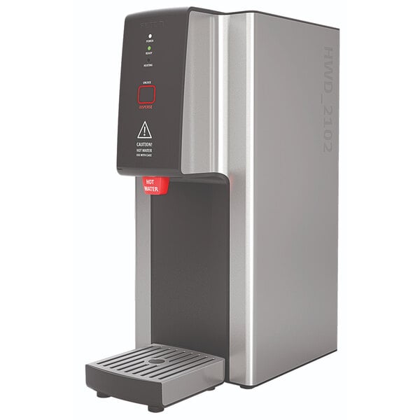 A silver and black Fetco hot water dispenser with a black push-button cover.