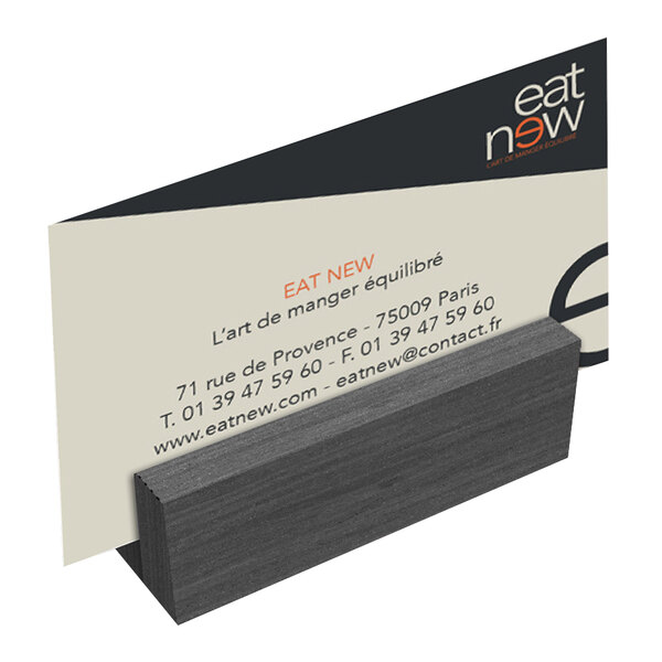 A close-up of a Menu Solutions ash wood mini card holder with a business card in it.