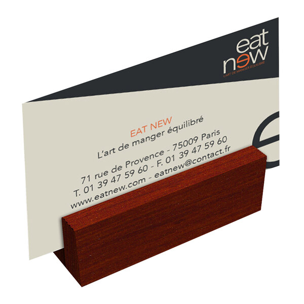 A mahogany wood mini card holder on a table with a business card in it.