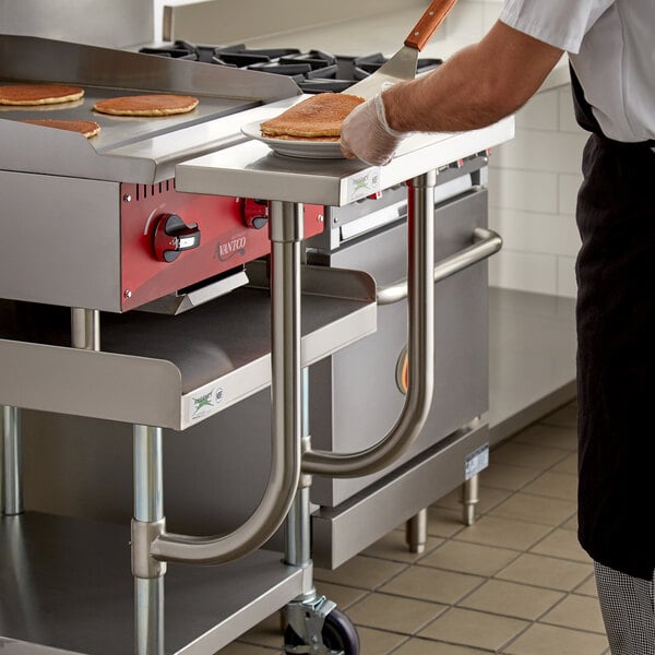 A person cooking pancakes on a Regency stainless steel work surface.