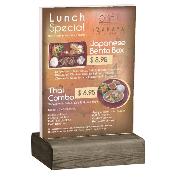 A Menu Solutions clear acrylic table tent with a weathered walnut wood base holding a menu on a table.