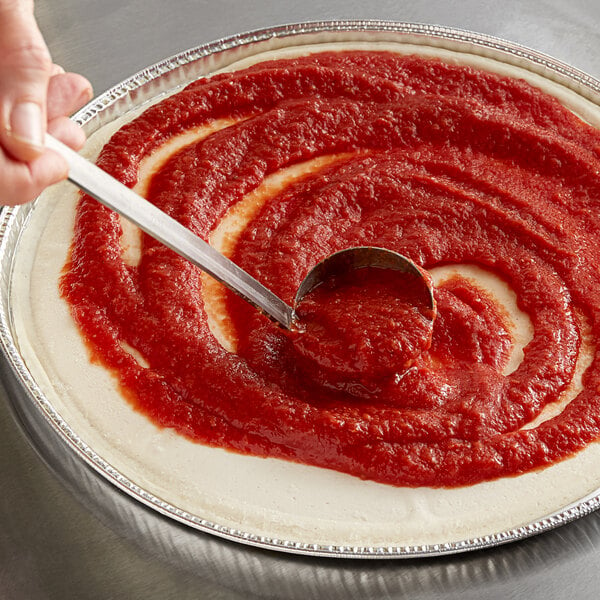 pizza sauce being spread on pizza dough
