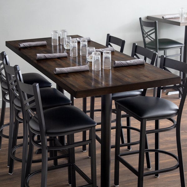 A Lancaster Table & Seating wooden butcher block table with chairs and glasses on it.