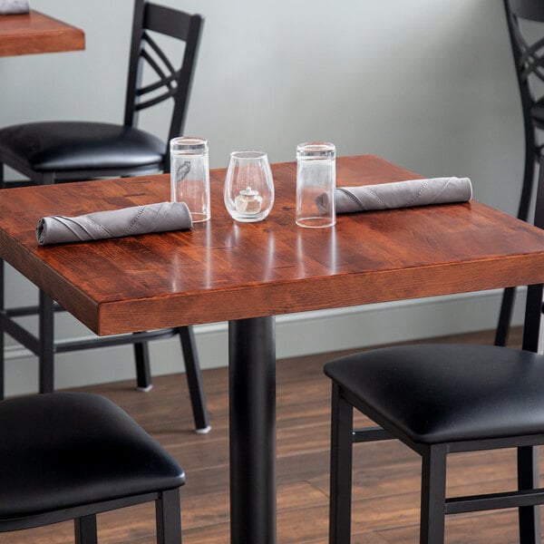 A Lancaster Table & Seating mahogany butcher block table with glasses and napkins on it.