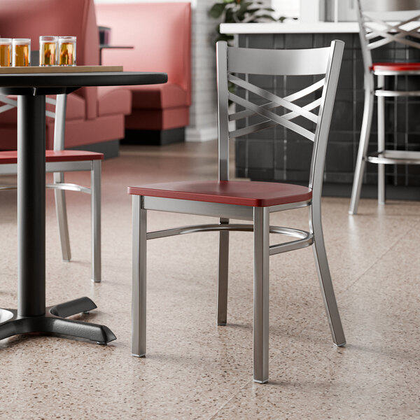 A metal cross back chair with a mahogany wood seat and a clear coat finish.