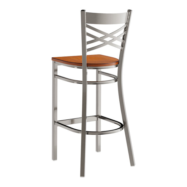 A metal bar stool with a cross back design and an antique walnut wood seat.