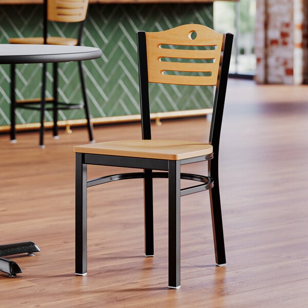 A Lancaster Table & Seating wooden side chair with natural wood seat and back on a restaurant floor.