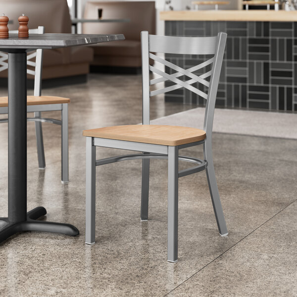 A Lancaster Table & Seating cross back chair with natural wood seat at a table in a restaurant.