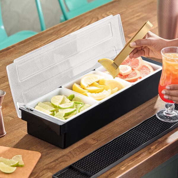 A three-compartment condiment bar filled with sliced citrus fruits on a wooden counter.