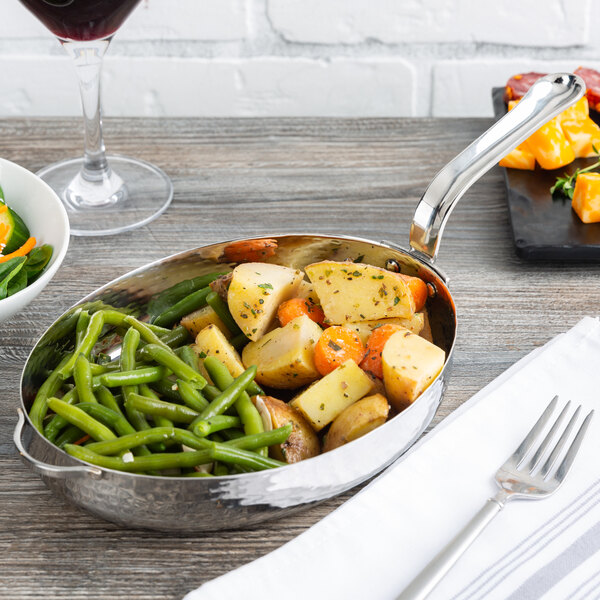 An American Metalcraft stainless steel skillet with vegetables and a fork on a table.