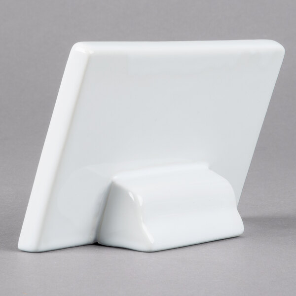 A white rectangular ceramic card sign on a gray surface.
