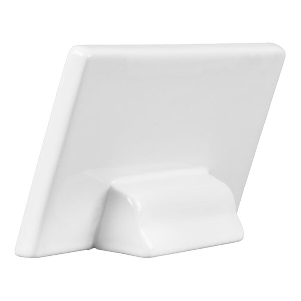 A white, rectangular ceramic object with a built-in stand, viewed from the back at an angle.
