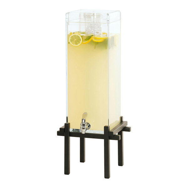 A Cal-Mil black beverage dispenser with lemons and a yellow liquid in a glass.