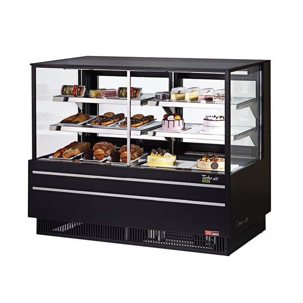 A black Turbo Air bakery display case with flat glass shelves holding various types of baked goods.