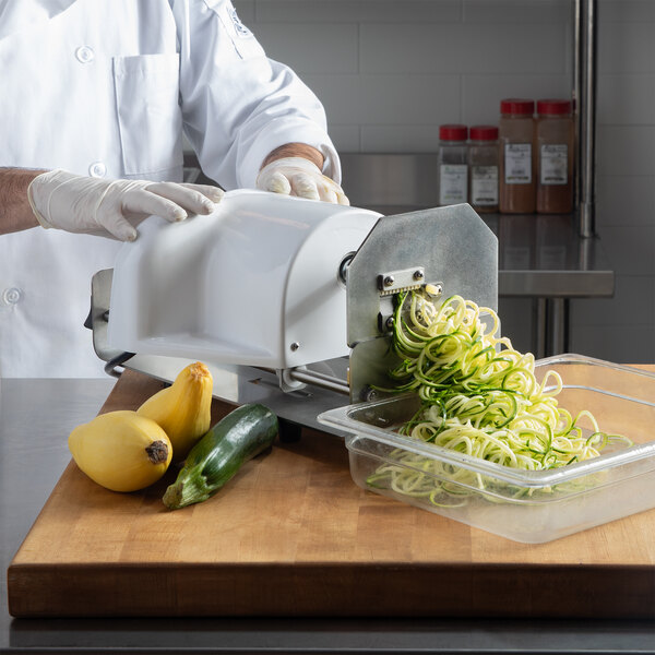 A chef using a Nemco Powerkut vegetable noodler to make zucchini noodles.